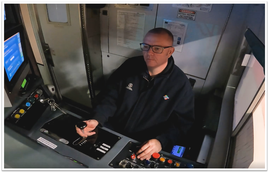 A man operating a train in the drivers cabin